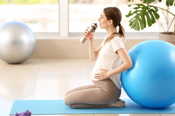 Bela mulher grávida bebendo água durante o treinamento em ginásio — Fotografia de Stock