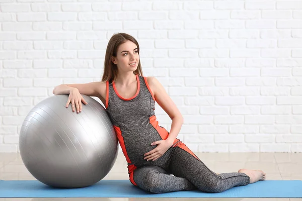 Mulher grávida bonita com treinamento fitball perto da parede de tijolo branco — Fotografia de Stock