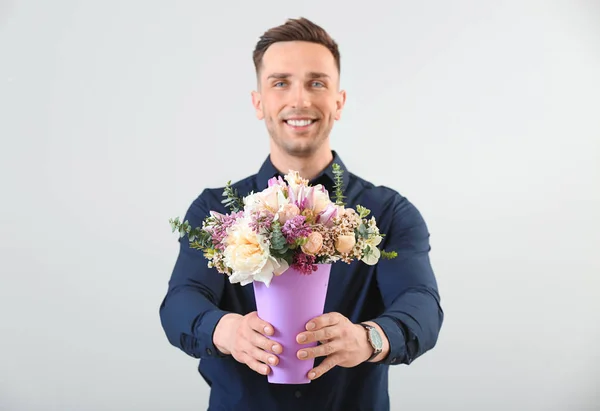 Hombre guapo con ramo de hermosas flores sobre fondo claro —  Fotos de Stock