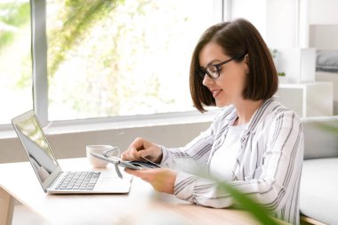 Evde kredi kartları ve dizüstü bilgisayar alışveriş online genç kadın