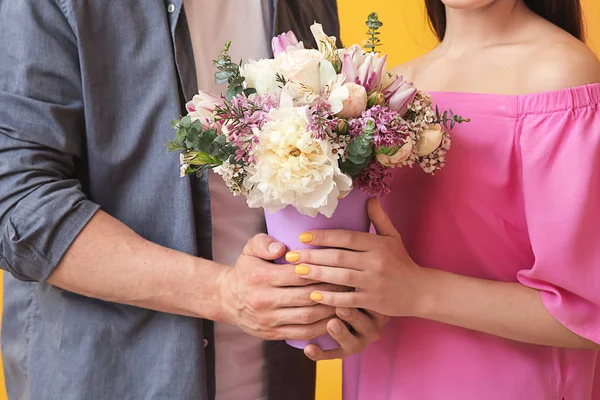 Coppia giovane con mazzo di bei fiori su sfondo a colori, primo piano — Foto Stock