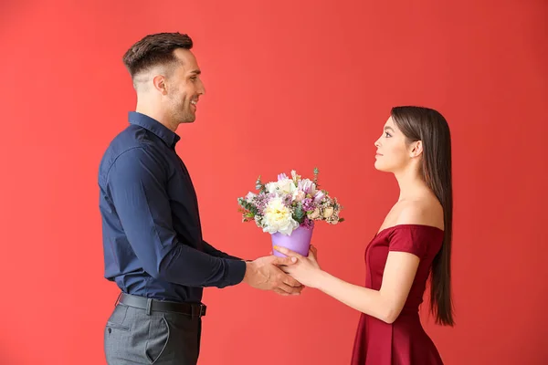 Frau erhält Blumen von jungem Mann auf farbigem Hintergrund — Stockfoto