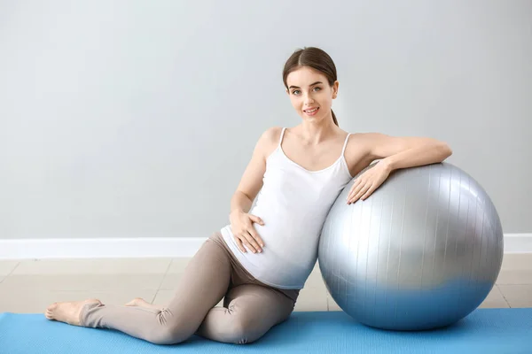 Mulher grávida bonita com treinamento fitball perto da parede cinza — Fotografia de Stock