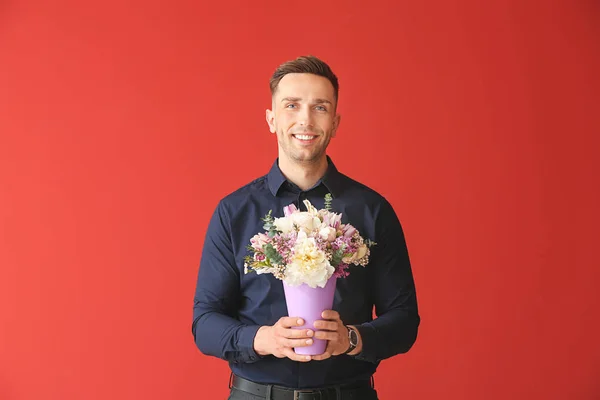Handsome man with bouquet of beautiful flowers on color background — Stock Photo, Image