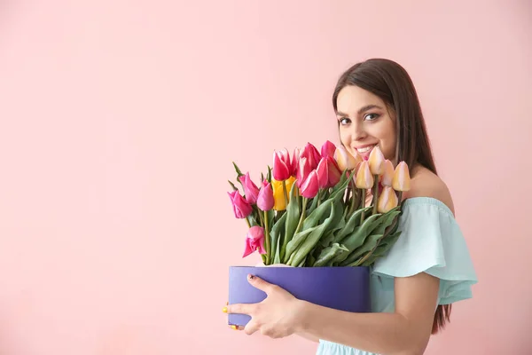 色の背景上の花の花束と美しい若い女性 — ストック写真