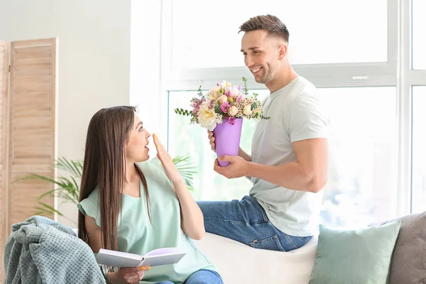 Marido saludando a su esposa con ramo de flores en casa — Foto de Stock