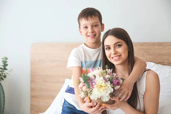 Young mother and son with bouquet of beautiful flowers at home — Stock Photo, Image