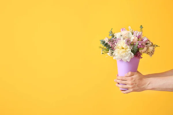 Young man with bouquet of beautiful flowers on color background