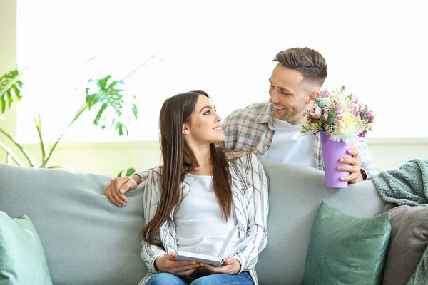 Marido saludando a su esposa con ramo de flores en casa — Foto de Stock