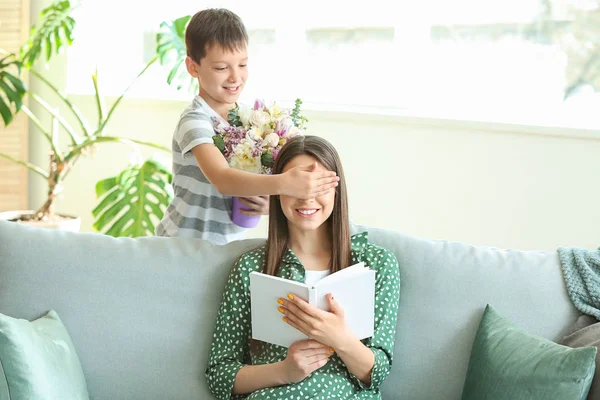 Little son greeting his mother with bouquet of flowers at home — Stock Photo, Image