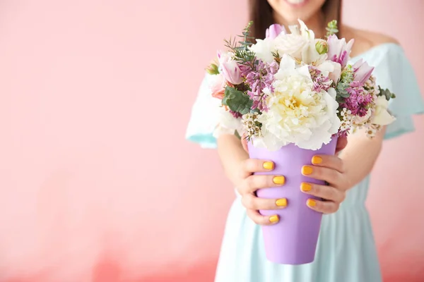 Belle jeune femme avec bouquet de fleurs sur fond de couleur — Photo