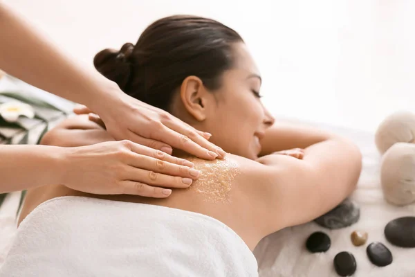 Young woman undergoing treatment with body scrub in spa salon — Stock Photo, Image
