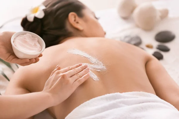 Young woman undergoing treatment with body scrub in spa salon — Stock Photo, Image