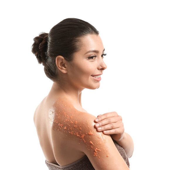 Красивая молодая женщина применяет скраб для тела на белом фоне
