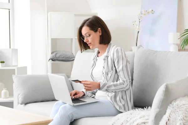 Young woman with credit card and laptop shopping online at home — Stock Photo, Image