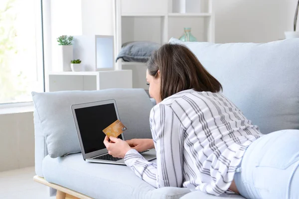 Young woman with credit card and laptop shopping online at home — Stock Photo, Image