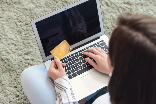 Young woman with credit card and laptop shopping online at home — Stock Photo, Image