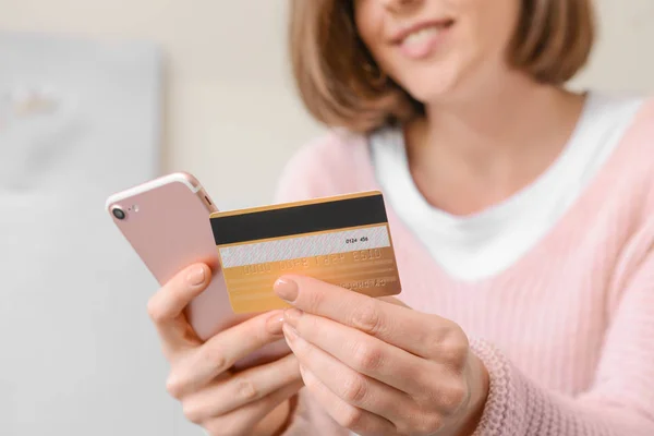Молода жінка з кредитною карткою та покупками мобільних телефонів онлайн вдома, крупним планом — стокове фото