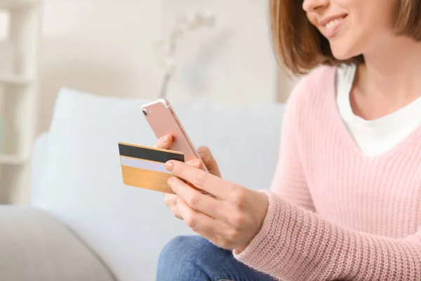 Young woman with credit card and mobile phone shopping online at home, closeup — Stock Photo, Image