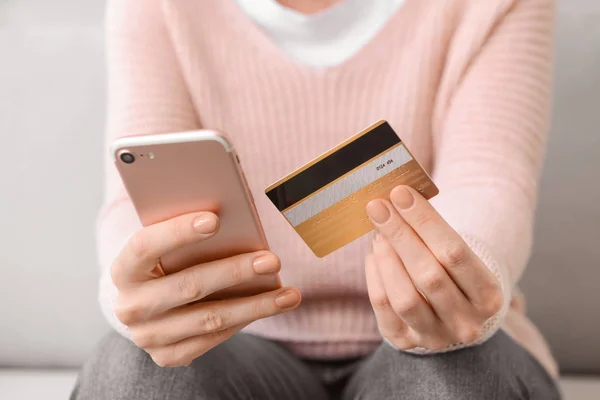 Молода жінка з кредитною карткою та покупками мобільних телефонів онлайн вдома, крупним планом — стокове фото