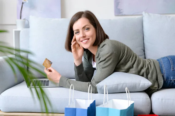 Mujer joven con tarjeta de crédito y ordenador portátil de compras en línea en casa — Foto de Stock