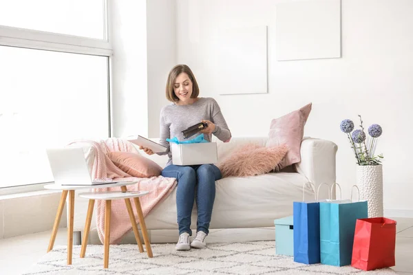 Joven mujer abriendo el paquete con nueva compra en casa — Foto de Stock