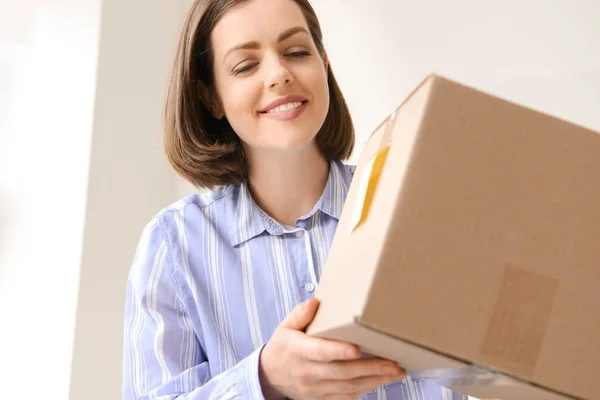 Young woman with parcel at home — Stock Photo, Image