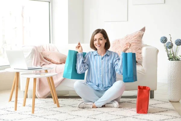 Mujer joven con bolsas de compras sentada en casa — Foto de Stock