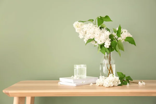 Vackra lila blommor med böcker på bordet mot färg bakgrund — Stockfoto