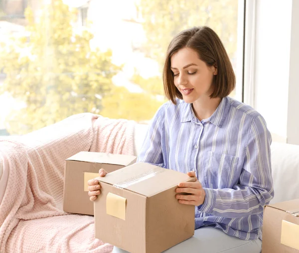 Jonge vrouw met pakket thuis — Stockfoto