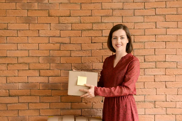 Young woman with parcel on brick wall background