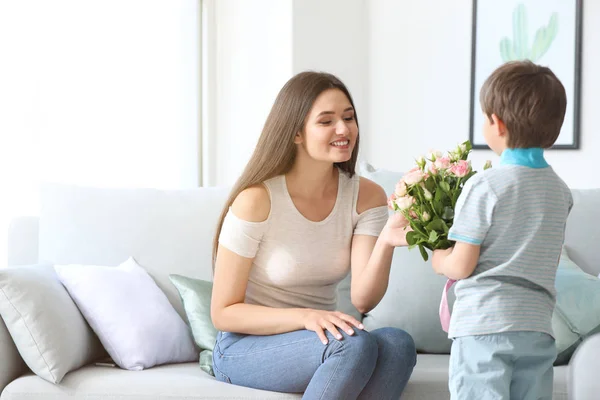 Син вітає матір з букетом квітів вдома — стокове фото