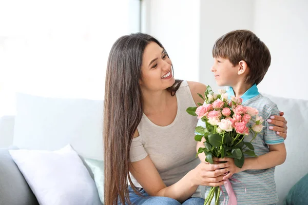 Zoon groet zijn moeder met boeket van bloemen thuis — Stockfoto