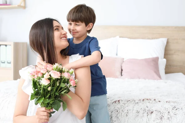 Feliz madre e hijo con ramo de flores en casa — Foto de Stock