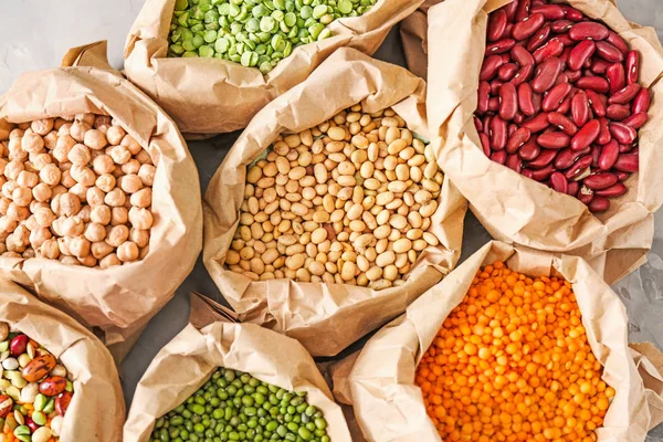 Zakken met verschillende peulvruchten op tafel — Stockfoto