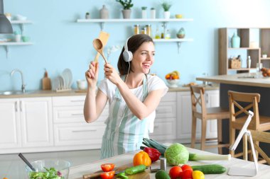 Mutfakta yemek yaparken müzik dinleyen güzel genç kadın