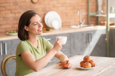 Güzel genç bir kadın mutfakta kahvaltı yapıyor.
