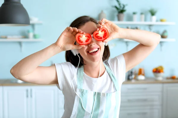 Mujer joven divertida con tomate en la cocina —  Fotos de Stock