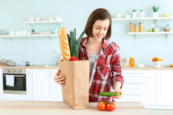 Junge Frau mit Tasche voller Produkte in Küche — Stockfoto