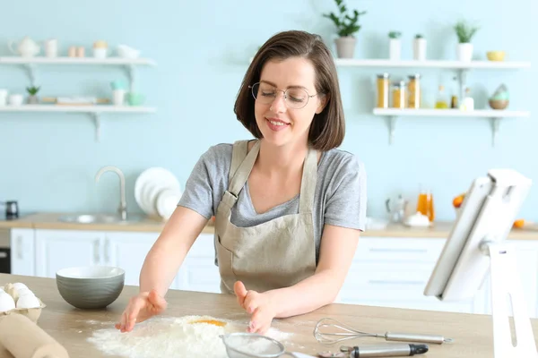 Beautiful young woman cooking pastry in kitchen — Stock Photo, Image