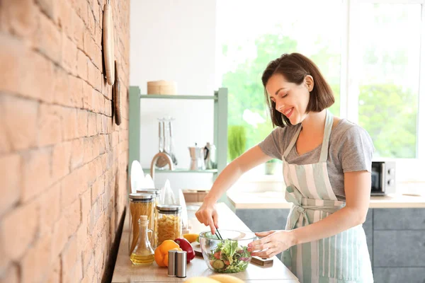 Hermosa mujer joven haciendo ensalada fresca en la cocina —  Fotos de Stock