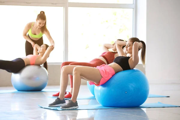 Jovens mulheres esportivas fazendo exercícios com fitballs no ginásio — Fotografia de Stock