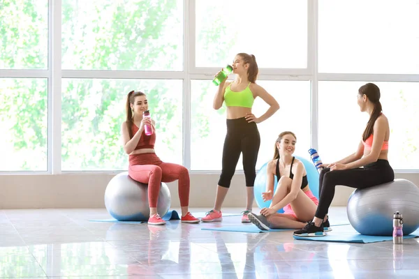 Jovens mulheres esportivas com fitballs bebendo garrafa no ginásio — Fotografia de Stock