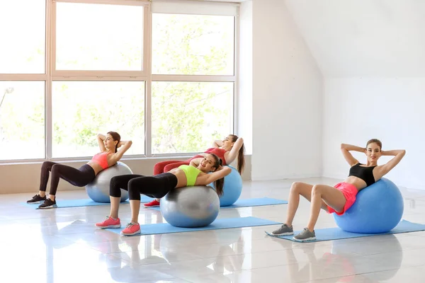 Jovens mulheres esportivas fazendo exercícios com fitballs no ginásio — Fotografia de Stock