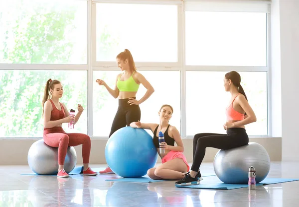年轻的运动女性与健身球在健身房喝瓶子 — 图库照片
