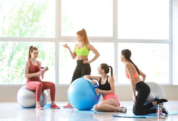 Jovens mulheres esportivas com fitballs bebendo garrafa no ginásio — Fotografia de Stock