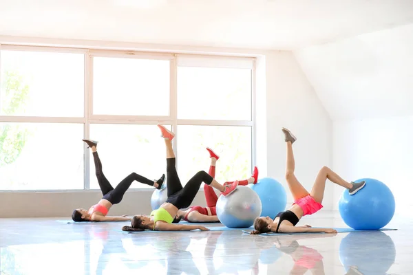 Jóvenes deportistas haciendo ejercicios con fitballs en el gimnasio —  Fotos de Stock