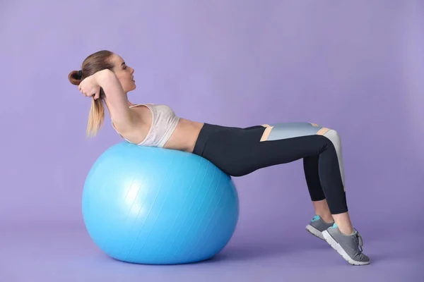 Young sporty woman doing exercises with fitball on color background — Stock Photo, Image