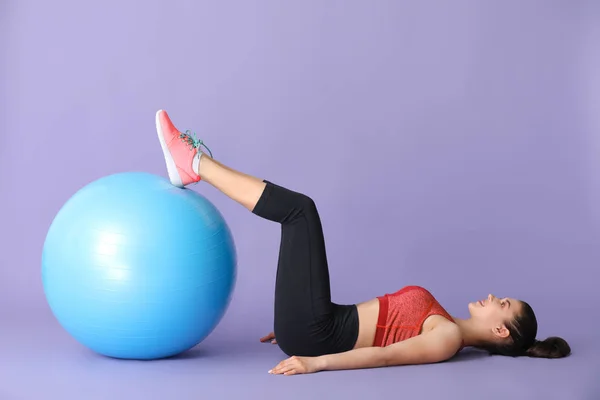 Młoda sportowa kobieta robi ćwiczenia z FitBall na kolorowym tle — Zdjęcie stockowe