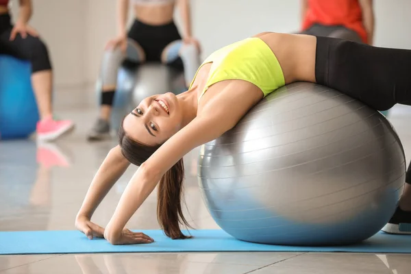 Joven mujer deportiva haciendo ejercicios con fitball en el gimnasio —  Fotos de Stock